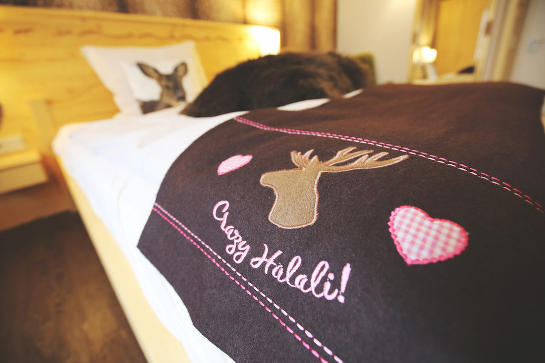 Bayrisches dunkel-blaues Tuch mit Hirschkopf und weißem Text "Crazy Halali!" auf einem Holzbett