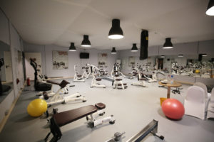 Weißer Raum mit Fitnessgeräten und Spiegeln an den Wänden