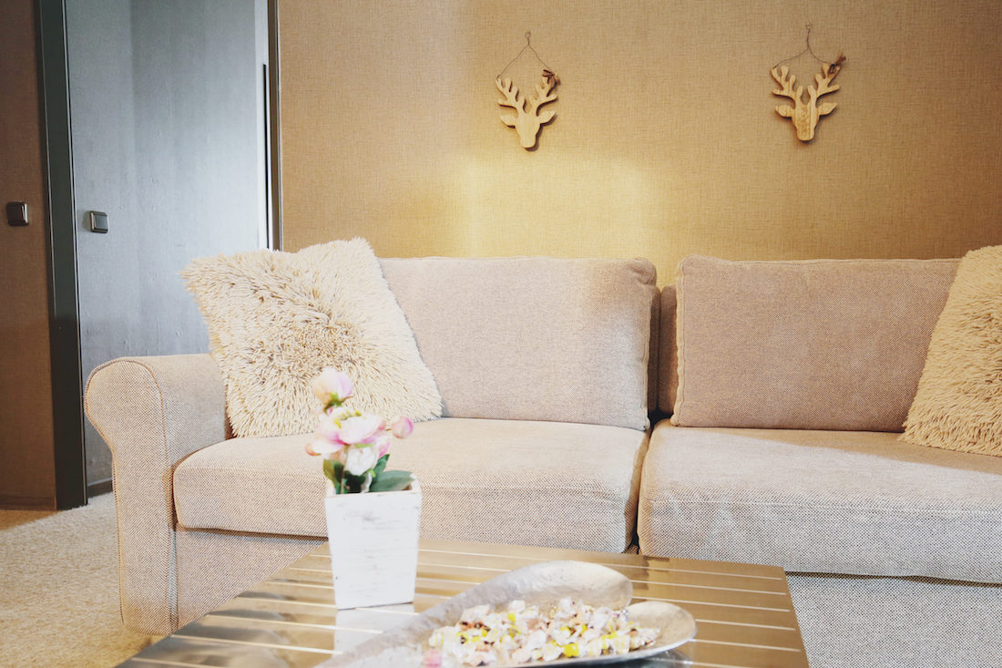 Gemütliches Sofa in beige, goldener Tisch mit Dekoration und Bonbons