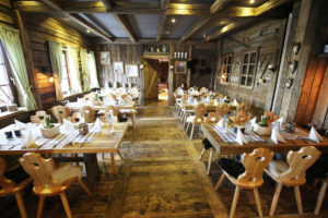 Traditionelles Restaurant mit 6 Holztischen, Holzstühlen und in einem Raum mit vielen dunkleren Holzelementen