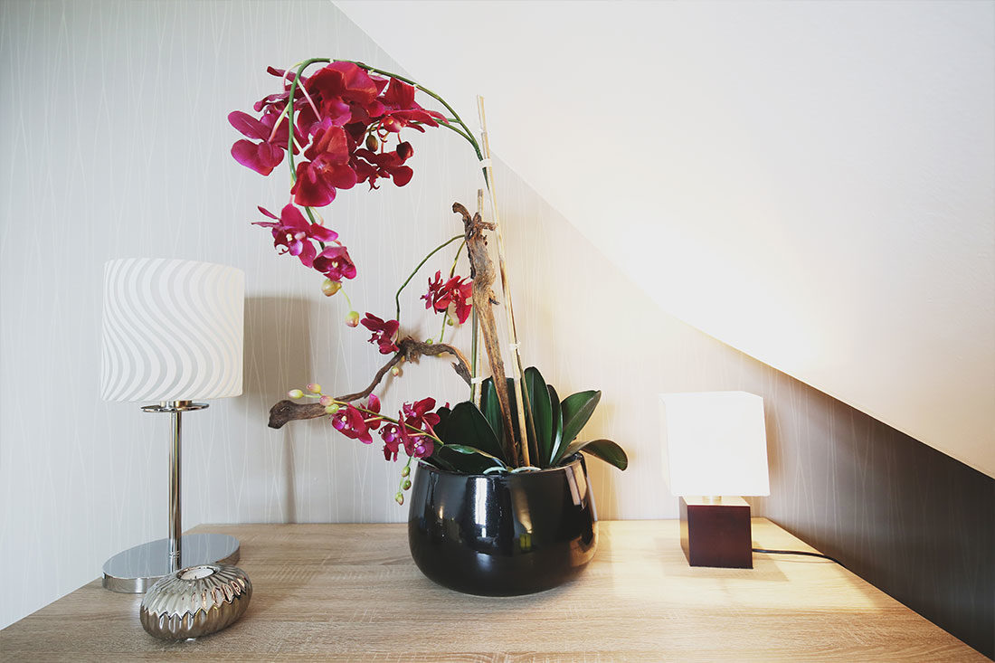 Holztisch mit roter Blume und leuchtender Tischlampe