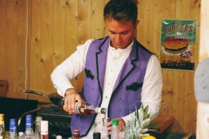 Junger Mann mit braunen kurzen Haaren und lila Weste schüttet Ramazotti aus