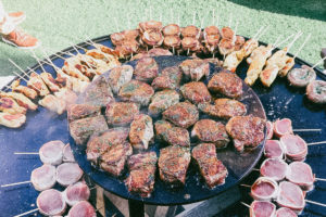 Großer runder zweistöckiger Grill mit viel Fleisch und Fleischspießen