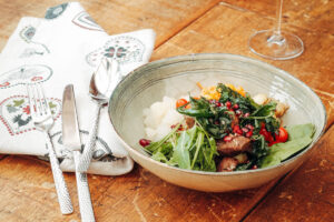Salat mit Fleisch in grauer Schale auf einem Holztisch