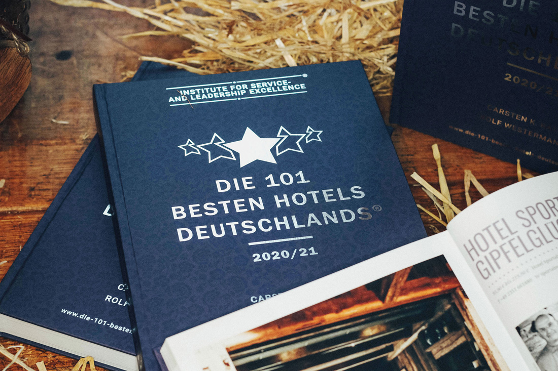 buch2 Die 101 besten Hotels Deutschlands, blaues Buchcover, unten ein aufgeschlagenes Buch