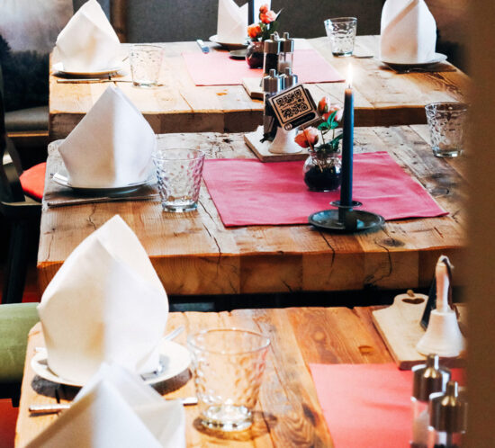 Nahaufnahme von drei massiven Holztischen, die einladend gedeckt sind